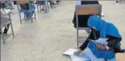  ?? AP ?? ▪ Jahantab Ahmadi writes the exam with her daughter on her lap.