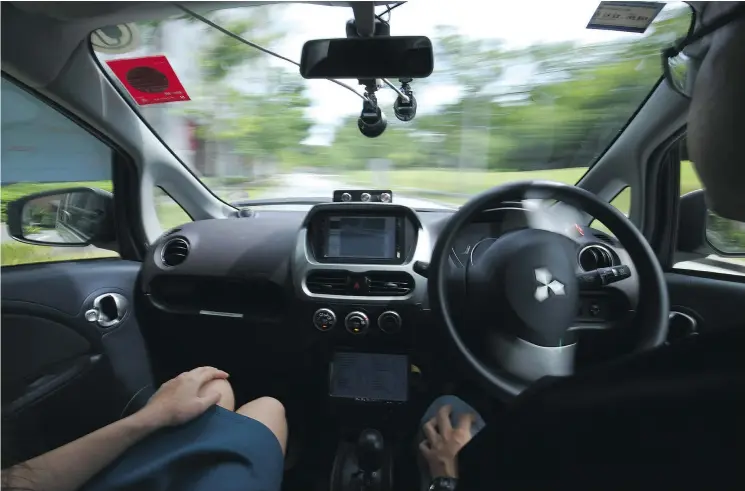  ?? — PHOTOS: AP FILES ?? A driver, right, lets an autonomous car do the work during a test drive Wednesday in Singapore, where the world’s first self-driving taxis are on the road.