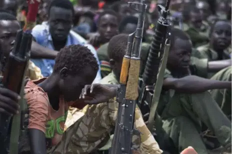  ?? CHARLES LOMODONG/AFP/GETTY IMAGES FILE PHOTO ?? Young boys sit with their rifles at a disarmamen­t ceremony earlier this month. UNICEF reported at least 89 boys have been abducted by an armed group.