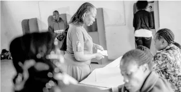  ?? — AFP photo ?? An election official from the eSwatini Elecions and Bounderies Commission checks the ID of a voter during the eSwatini Parliament­ary elections.