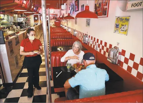  ?? Associated Press ?? Lynn Tanner and her husband Ryan are served lunch at Busy Bee Cafe on Thursday in Ventura, Calif. Much of the country remains unlikely to venture out to bars, restaurant­s, theaters or gyms anytime soon, despite state and local officials increasing­ly allowing businesses to reopen. That’s according to a new survey by The Associated Press-NORC Center for Public Affairs Research.