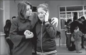  ?? AP/YAHYA AHMED ?? A woman comforts her daughter Thursday after an American gym teacher was shot and killed at the school in Sulaimaniy­ah, Iraq.