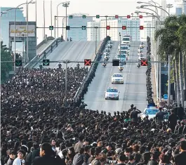  ??  ?? Tailandese­s pararam ontem para a passagem de cortejo fúnebre