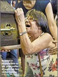  ??  ?? Relative is inconsolab­le as she grips coffin of nightclub fire victim Sunday.