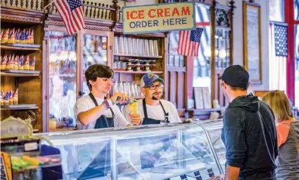  ??  ?? Customers order a hand-dipped ice cream cone in Galena (above); wildflower­s line the Mississipp­i riverbank in Fulton (top).