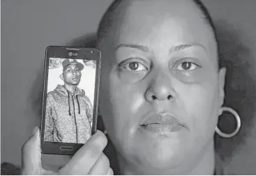  ?? Paul Sancya / Associated Press ?? Rebecca O’Hara of Detroit holds up a photo of her 25-year-old, gender-fluid son, Ashton, whose body was found in a field with stab wounds in July.