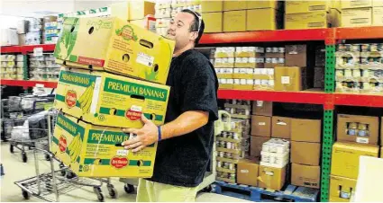  ?? David Hopper/For the Chronicle ?? Volunteer Jimmy Born of Tomball carries boxes of fruit at the nutrition center in the Northwest Assistance Ministries building on Kuykendahl Road in northwest Harris County.