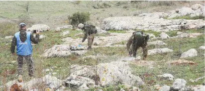  ?? (Al-Manar) ?? IDF TROOPS operate yesterday beyond Israel’s border fence with Lebanon in search of cross-border Hezbollah tunnels, as a UNIFIL peacekeepe­r monitors their progress.