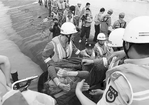  ?? AFP / Gett y Imag es ?? An elderly survivor is carried onto the river bank on Tuesday after being rescued from the Eastern Star cruise ship,
which sank in the Yangtze River near Jianli, China, with 458 people aboard, touching off a frantic rescue effort.