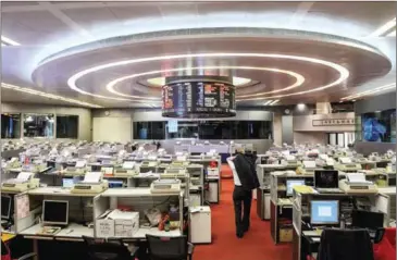  ?? ANTHONY WALLACE/AFP ?? A trader puts on his jacket as he leaves the floor of the stock exchange after the start of the Shenzhen-Hong Kong Stock Connect yesterday. The long-delayed trading link between the exchanges of Hong Kong and Shenzhen in China got off a bad start, with...