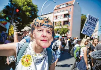  ?? Foto: Christoph Soeder, dpa ?? Eine Frau trägt bei der Demonstrat­ion in Berlin eine Merkel-Maske mit der Aufschrift „Bye bye Demokratie“. Andere kamen zum Protestzug mit Schildern wie „Wir sind die 2. Welle“.