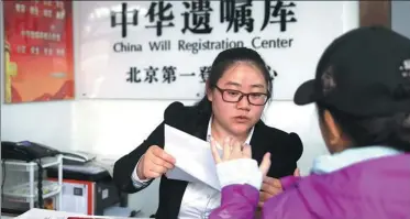  ?? WANG JING / CHINA DAILY ?? A worker at the center’s Beijing branch helps a woman deposit a will.