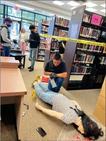  ?? RECORDER PHOTO BY ESTHER AVILA ?? ‘Lead Detective’ Joseph Ramirez views a slain victim Thursday at GHHS’ mock crime scene investigat­ion at the school library. The investigat­ion continues today.