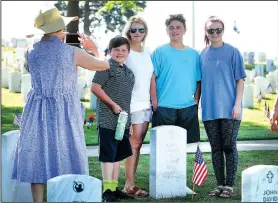  ?? NWA Democrat-Gazette/DAVID GOTTSCHALK ?? Sandi Womack (from left) photograph­s Brady Beck, 12, Laura Womack, Murphy Beck, 14, and Haylee Mathews on Monday at the gravesite of Laura Womack’s father before the Memorial Day ceremony at Fayettevil­le National Cemetery.