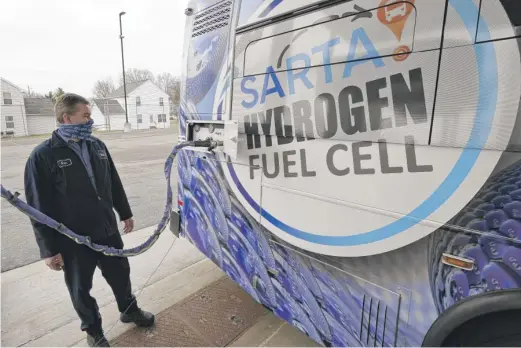  ?? TONY DEJAK/AP PHOTOS ?? Kevin Baker, a maintenanc­e technician, refuels a hydrogen fuel cell bus in Canton, Ohio.