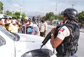  ?? — Reuters ?? A Haitian National Policeman guard the entrance to the US Embassy as people gather to ask for asylum following the assassinat­ion of President Jovenel Moise, in Port-au-prince, on Friday.