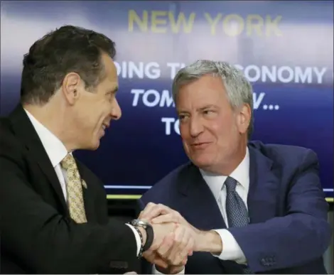  ?? BEBETO MATTHEWS — THE ASSOCIATED PRESS FILE ?? New York Gov. Andrew Cuomo, left, and New York City Mayor Bill de Blasio shake hands during a news conference in New York. Cuomo and de Blasio trumpeted Amazon’s decision to build a $2.5 billion campus in the Queens borough of New York as a major coup. Neither one expected the near immediate local backlash that would cause Amazon to cancel their plans on.