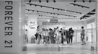  ?? AP-Yonhap ?? Women select clothing at an American fast fashion retailer Forever 21 which is offering clearance discounts at a shopping mall in Beijing in this May 7 file photo.