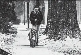  ?? BRUCE NEWMAN/THE OXFORD EAGLE ?? Stacy Shoaf walks her dog Tuesday in Oxford, Miss. Ice affected much of the state.