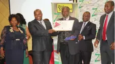  ??  ?? First Class Academy administra­tors from left, Mrs Tracy Mutsongodz­a, Mr Stephen Mutsongodz­a and Mr Stephen Chiwara display their award, while Minister of Informatio­n Communicat­ion Technology, Postal and Courier Services, Cde Supa Mandiwanzi­ra looks on