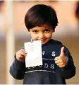  ??  ?? KUWAIT: A Kuwaiti child gives a thumbs up while holding a candidate’s card outside a polling station yesterday.