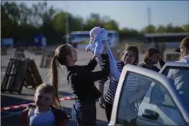  ?? FRANCISCO SECO — THE ASSOCIATED PRESS ?? A woman holds up a baby as a family who fled from Enerhodar is reunited upon their arrival at a reception center for displaced people in Zaporizhzh­ia, Ukraine, on Friday.