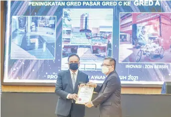  ?? — Bernama photo ?? Reezal (left) hands over certificat­e and plaque to Tuan Zainal Abidin Tuan Yusuf of Kota Bharu Municipal Council