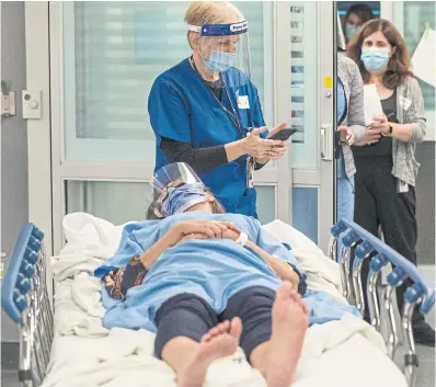  ?? RICK MADONIK TORONTO STAR ?? A member of the patient transport team is checking a hospital smartphone before taking “Henry” to the medical imaging department for a hip X-ray. Patients are tracked throughout their hospital stay via their electronic medical record.