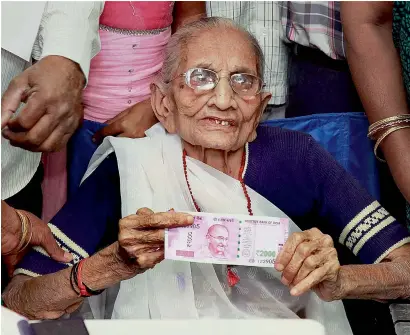  ?? — PTI ?? Prime Minister Narendra Modi’s mother Heeraben Modi shows the 2000 rupees note after exchanging old 500 note at a bank in Gandhinaga­r, Gujarat, on Tuesday.