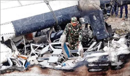  ?? PRAKASH MATHEMA/AFP ?? A Nepali rescue worker looks through wreckage of an airplane that crashed near the internatio­nal airport in Kathmandu on Monday.