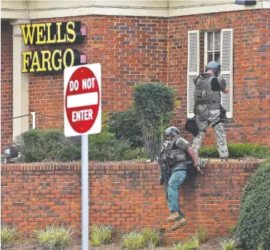  ?? THE ASSOCIATED PRESS ?? Police officers take up positions Friday outside a Wells Fargo Bank in Marietta, Ga., following reports of a man claiming to have a bomb.