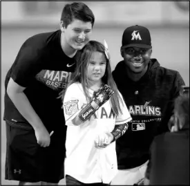  ?? WILFREDO LEE / ASSOCIATED PRESS ?? Hailey Dawson, 8, poses with her brother Zach, left, and the Miami Marlins’ Lewis Brinson after she used her 3D-printed robotic hand to throw out a ceremonial first pitch Aug. 10 in Miami.