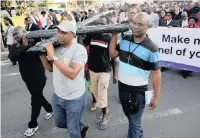  ?? African News Agency (ANA) ?? FOREIGN nationals take a turn at carrying the cross during the Diakonia Council of Churches Good Friday procession through Durban, after a sermon denounced xenophobia, among other social ills that threaten peace before next month’s election.