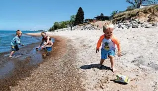  ?? JOHN J. KIM/CHICAGO TRIBUNE ?? Gabriel, 3, chases after a plastic bag as his mother, Briana Lambooy, and 4-year-old brother, Theo, play at Ogden Dunes Beach in Portage Township, Indiana, on May 14.