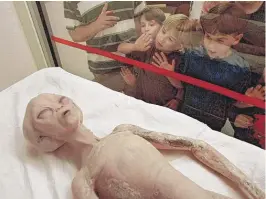  ?? | AP FILE PHOTO ?? Children eye a model of an alien on display inside the Internatio­nal UFO Museum and Research Center in Roswell, New Mexico, in 1997. The museum, which is free to the public, receives visitors from all over the world.