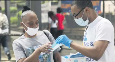  ?? MARK LENNIHAN—ASSOCIATED PRESS ?? In this July 8, 2020, file photo, Stephane Labossiere, right, with the Mayor’s Office of Immigrant Affairs, hands out masks and printed informatio­n about free COVID-19 testing in Brooklyn being offered by NYC Health + Hospitals, in New York.