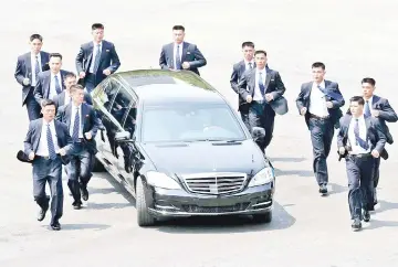  ??  ?? North Korean bodyguards jog next to a car carrying Jong Un returning to the North for a lunch break after a morning session of the interKorea­n summit at the truce village of Panmunjom. — AFP photo