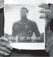  ?? FREDERIC J. BROWN/GETTY-AFP ?? A fan holds a photograph of Chadwick Boseman during a candleligh­t vigil for the actor Saturday in Los Angeles.