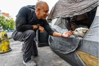  ?? DAMIAN DOVARGANES/ASSOCIATED PRESS ?? Dr. Kwane Stewart approached a dog named Popcorn, who was protecting his owner’s tent in the Skid Row area of Los Angeles earlier this month.