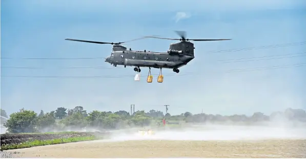  ??  ?? An RAF Chinook helicopter lands on the side of the River Steeping, which burst its bank and flooded seventy properties in the nearby town of Wainfleet
