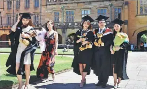  ?? WILLIAM WEST / FOR CHINA DAILY ?? Students from China pose for photos after graduating from a business studies course at the University of Sydney in October last year.