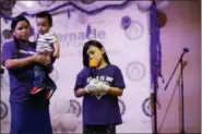  ?? GREGORY BULL — THE ASSOCIATED PRESS ?? Holding her youngest son, Alma Vazquez stands next to her stepdaught­er, Neveah Tomas, as she sings a song at a church event in Fairfield, Ohio, on April 28, 2018. A cousin who sometimes cares for the children told Vazquez that she recently heard them saying that if their father was deported, they’d have to leave the country, too.