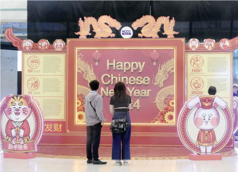  ?? BING GONZALES ?? SHOPPERS take time to read the Chinese horoscope installed at NCCC Mall VP as part of the approachin­g Chinese Lunar New Year on Feb. 10, 2024. In line with this, Malacañang declares Feb. 9 a special non-working holiday throughout the country.