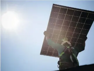  ?? MICHAEL NAGLE/BLOOMBERG FILES ?? A SolarCity Corp. employee installs one of the company’s solar panels. Elon Musk wants to merge Tesla with SolarCity, a company co-founded by his cousins and which he chairs.