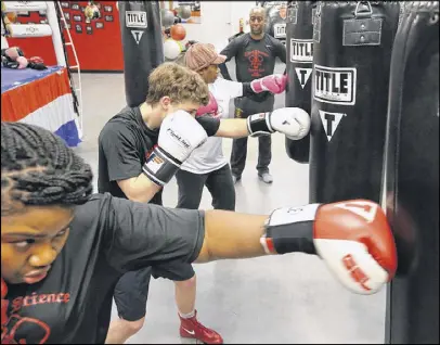  ?? CURTIS COMPTON / CCOMPTON@AJC.COM ?? Danielle Huggins (from left), Carter Coffie and Marty Lewis punch bags while Marty Hill teaches their boxing fitness class at Sweet Science Fitness Boxing Club last week in Doraville.