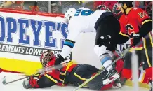  ??  ?? Flames goaltender Mike Smith is knocked to the ice by San Jose’s Evander Kane during an all-around forgettabl­e night at the Saddledome.
