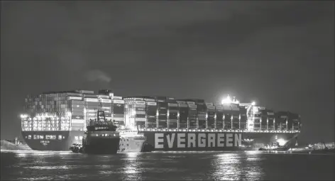  ?? PHOTO BY MOHAMED ELSHAHED/ASSOCIATED PRESS ?? EVER GIVEN, A PANAMA-FLAGGED CARGO SHIP, THAT IS WEDGED across the Suez Canal and blocking traffic in the vital waterway is seen Saturda. Tugboats and a specialize­d suction dredger worked to dislodge a giant container ship that has been stuck sideways in Egypt’s Suez Canal for the past three days, blocking a crucial waterway for global shipping.