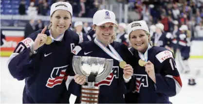  ??  ?? PLYMOUTH: US forward Meghan Duggan, left, defender Monique Lamoureux, center, and forward Brianna Decker pose with the winner’s trophy after the team defeated Canada 3-2 in overtime in the women’s world hockey championsh­ips, Friday, in Plymouth, Mich. — AP