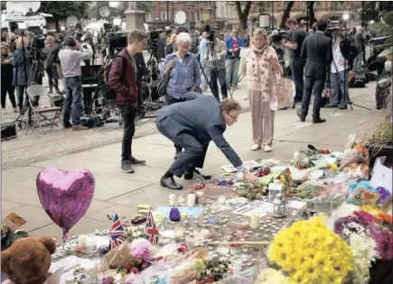  ??  ?? A man places flowers in Albert Square, Manchester, this week at the makeshift memorial site to the victims of Monday night’s terror attack at the Ariana Grande music concert.