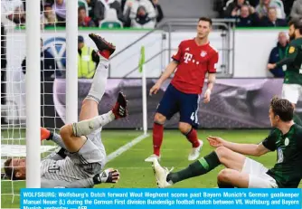  ?? — AFP ?? WOLFSBURG: Wolfsburg’s Dutch forward Wout Weghorst scores past Bayern Munich’s German goalkeeper Manuel Neuer (L) during the German First division Bundesliga football match between VfL Wolfsburg and Bayern Munich, yesterday.